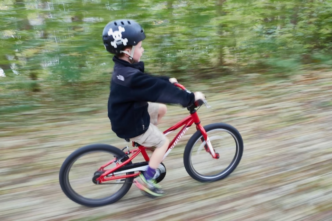 Niño pequeño en bicicleta recorriendo vía verde